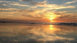 Une plage au coucher du soleil, avec une mer calme et un ciel dégagé.