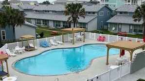 Una piscina con cubierta de madera, sillas de descanso y un área cercada.