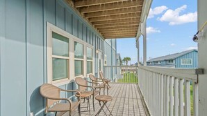 Eine überdachte Veranda mit Korbstühlen, einer Holzterrasse und Blick auf die Nachbarhäuser.