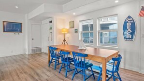Ein Essbereich mit einem Holztisch, blauen Stühlen, einer Lampe und einer Surfbrett-Dekoration.