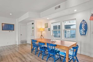 Enjoy meals in this dining area with a wooden table and four chairs, surrounded by a large window and framed artwork.