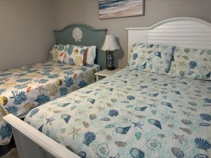 Un dormitorio con dos camas, cada una con cabecero y almohada a juego, y una mesita de noche con lámpara.