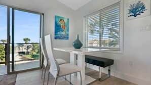 Ein modernes Zimmer mit Glastür zum Balkon, einem weißen Schreibtisch mit Stuhl, einem Bild und einer Dekovase.