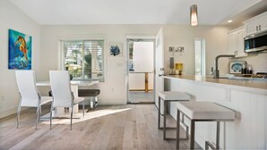 Eine moderne Küche mit weißen Schränken, einer Edelstahl-Mikrowelle und einer Bar.