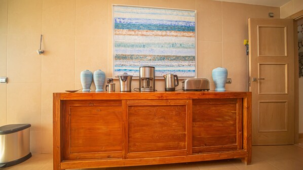 Un meuble en bois contenant des appareils de cuisine, avec deux vases bleus posés sur le dessus.