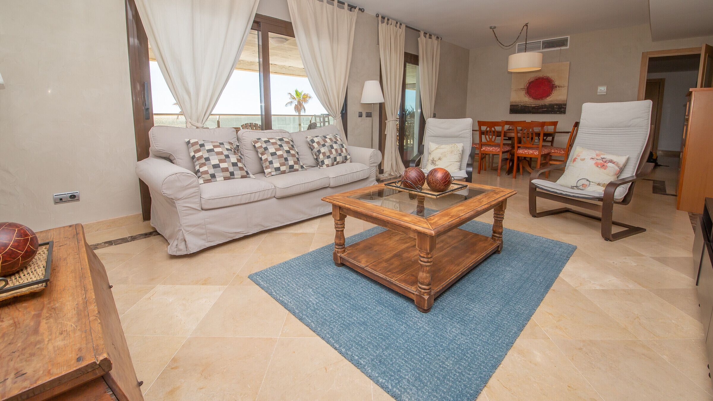 A living room with a sofa, a coffee table, a chair, and a dining table.