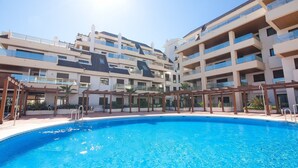 Um hotel moderno com piscina, várias varandas e uma área externa coberta.