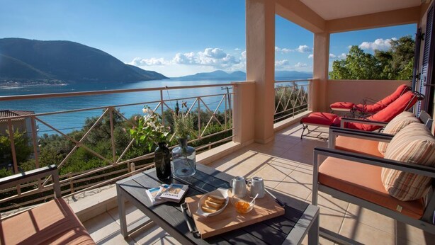 A balcony with a view of the sea and mountains, furnished with red chairs and a table with a tray of snacks. - Villa Eirini (Vasiliki Lefkada)