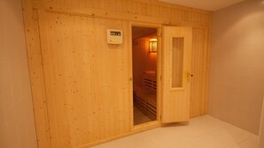 A wooden sauna room with a control panel on the wall and a door leading to a bench area. - Marina del Castillo 321 (Manilva)