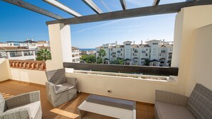 Ein Balkon mit Korbmöbeln, Blick auf Wohnhäuser und einen klaren Himmel.