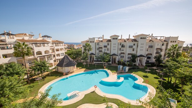 Ein Resort mit großem Schwimmbad, mehrstöckigen Gebäuden und Meerblick.