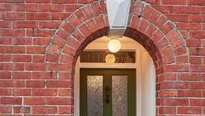A brick archway with a green door and a sign above it. - Tilldene (New Romney)