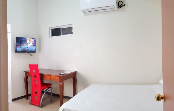 A room with a bed, a desk with a chair, a television, and an air conditioning unit. - Executive Room - 10 min from US Consulate - Flexible Check-in (juarez)