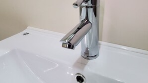 Un lavamanos moderno con grifo cromado y un desagüe.