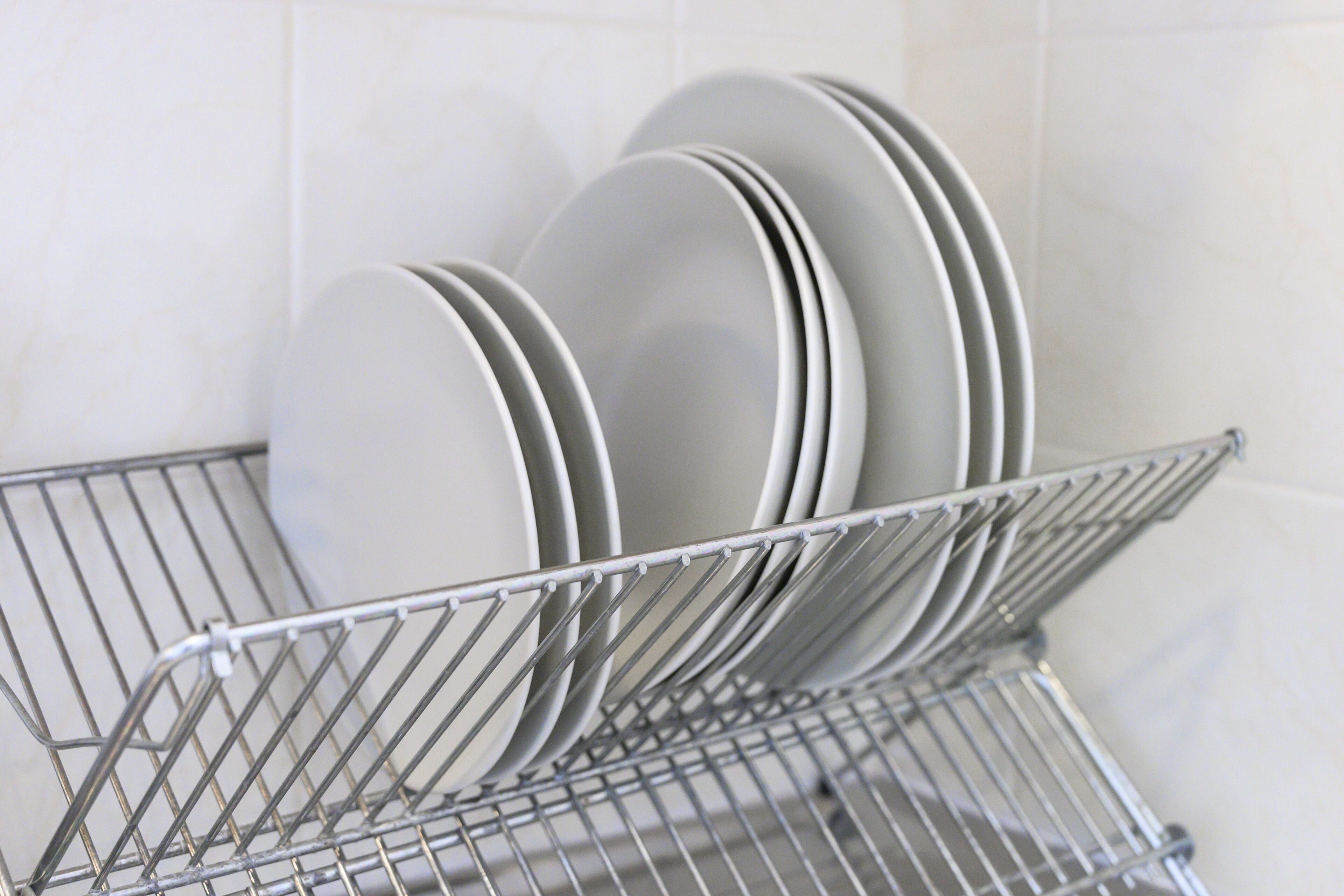 Un escurreplatos metálico con platos blancos dentro de una cocina.
