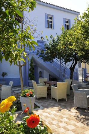 A courtyard with outdoor seating, a staircase, and a building with blue shutters. - Chroma Design Hotel and Suites (Nafplio)