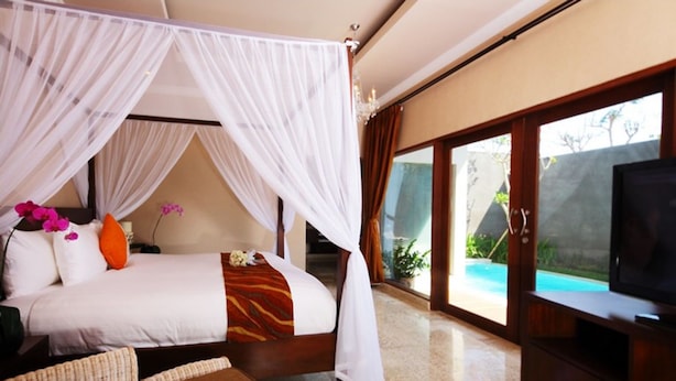 Un dormitorio con cama con dosel, televisión y vistas a una piscina.