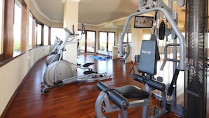 Une salle de sport équipée de machines de cardio, d’appareils de musculation et d’un tapis bleu sur le sol.