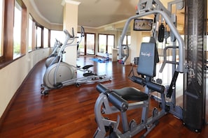 Een fitnessruimte met cardioapparatuur, gewichtstrainingsapparatuur en een blauwe mat op de vloer.