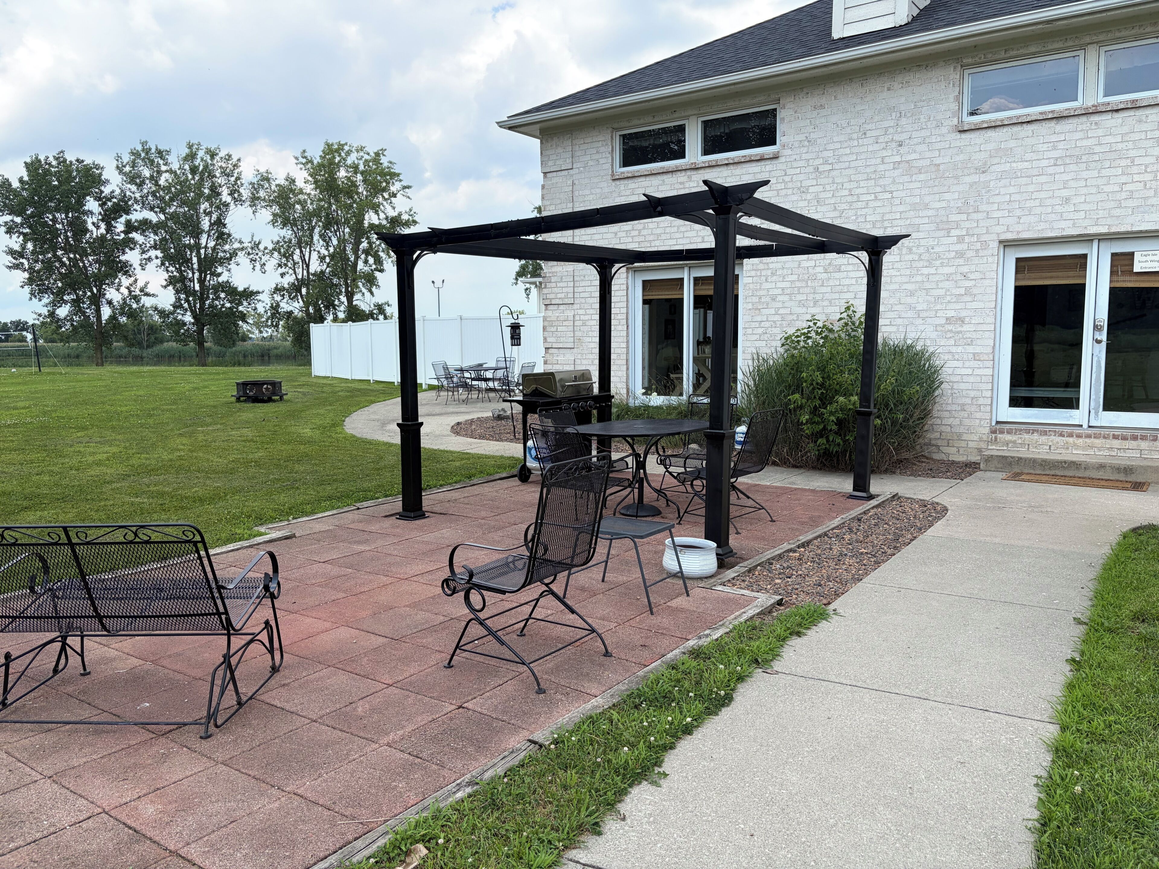 Une terrasse avec mobilier d’extérieur, une pergola et un espace barbecue.