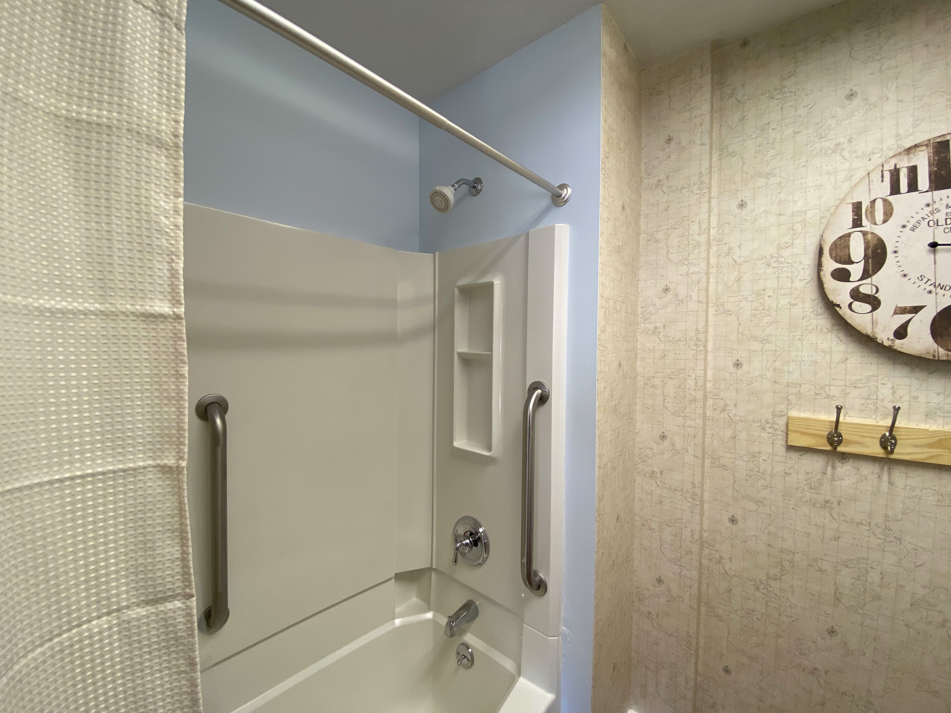 Une salle de bain avec une baignoire, une douche et une horloge au mur.