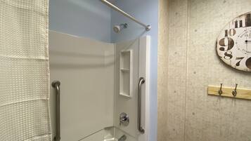 Une salle de bain avec une baignoire, une douche et une horloge au mur.