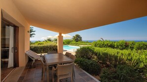 Un patio techado con piscina, mobiliario exterior y vista al mar.