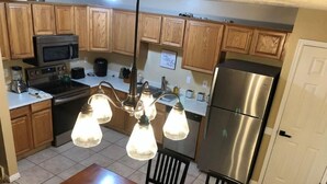 A kitchen with wooden cabinets, stainless steel appliances, and a dining table with chairs. - Great PRIVATE Family T-Home! Easy Access City & Mountains! (Layton)