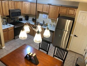 Compact kitchen with refrigerator, oven, and microwave, featuring a dining table and chairs.