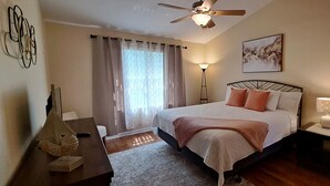 A bedroom with a bed, a desk, a chair, a lamp, a ceiling fan, and a window with curtains. - Poolside Days & Disney Nights! Spacious Family Friendly 3BR/2BA Condo (Kissimmee)