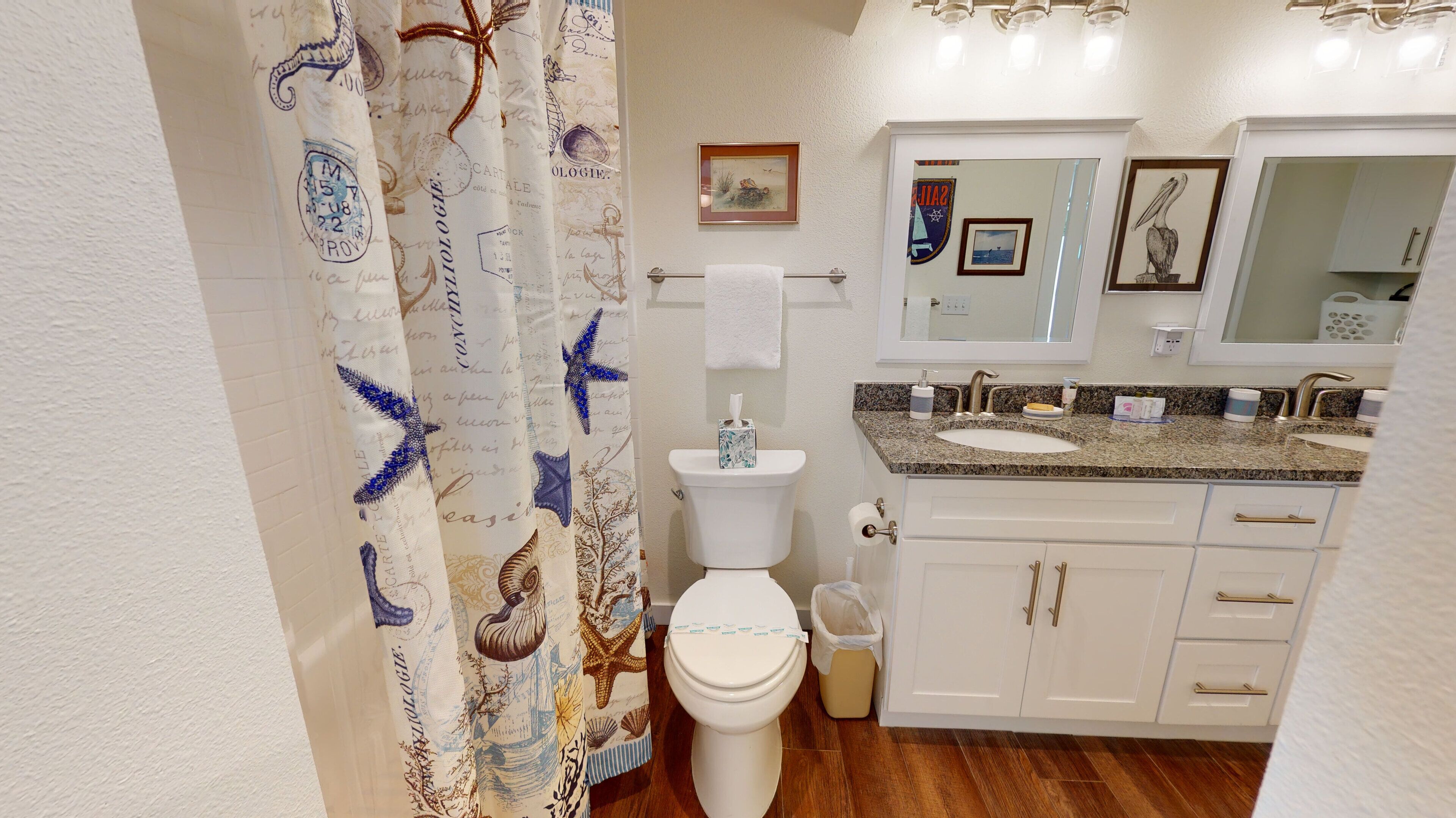 A bathroom with a white toilet, a sink with a granite countertop, and a mirror above the sink.