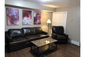 Relax in this stylish living room with a sofa, armchair, and vibrant artwork.