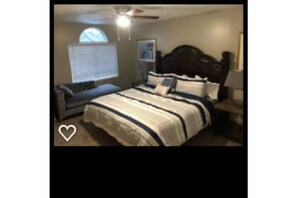 Relax in this inviting bedroom with a large bed, window, and comfortable seating area.