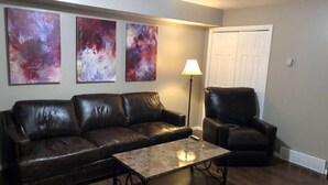 A living room with a dark brown leather sofa, a matching armchair, and a coffee table with a lamp. - Your Second Home. Big 2 Bedroom and 2 bathroom. (Clearfield)
