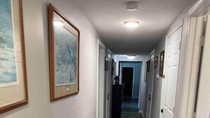 A hallway with wooden flooring, white walls, and framed pictures. - Rum River Retreat! Clean & Cozy on 15 acres! (Cambridge)