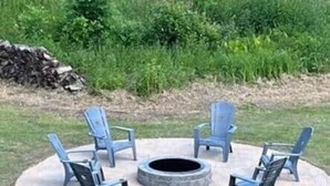 A circular fire pit with four Adirondack chairs around it, set on a stone pathway in a grassy area. - Rum River Retreat! Clean & Cozy on 15 acres! (Cambridge)