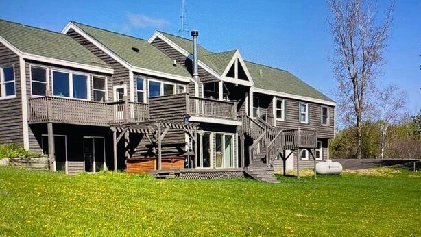 A two-story building with a covered porch and a staircase leading to the upper level. - Rum River Retreat! Clean & Cozy on 15 acres! (Cambridge)