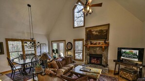 A spacious living room with a fireplace, wooden furniture, and a television. - Riverview Hideaway by Mountain Oasis | Dog-Friendly Riverview Cabin in Coosawattee (Ellijay)
