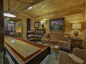 Une pièce chaleureuse avec une table de billard, des fauteuils en cuir, un canapé et une bibliothèque.