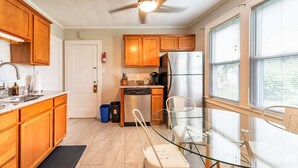 Una cocina moderna con armarios de madera, un refrigerador de acero inoxidable y una mesa de comedor de vidrio.