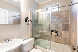 Un baño moderno con ducha de vidrio, lavamanos blanco y retrete.