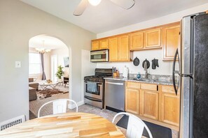 A modern kitchen with wooden cabinets, stainless steel appliances, and a dining area with a wooden table and chairs. - Spacious 4 BR/2 BA – 4 Min Walk to DT Ferndale! (Ferndale)