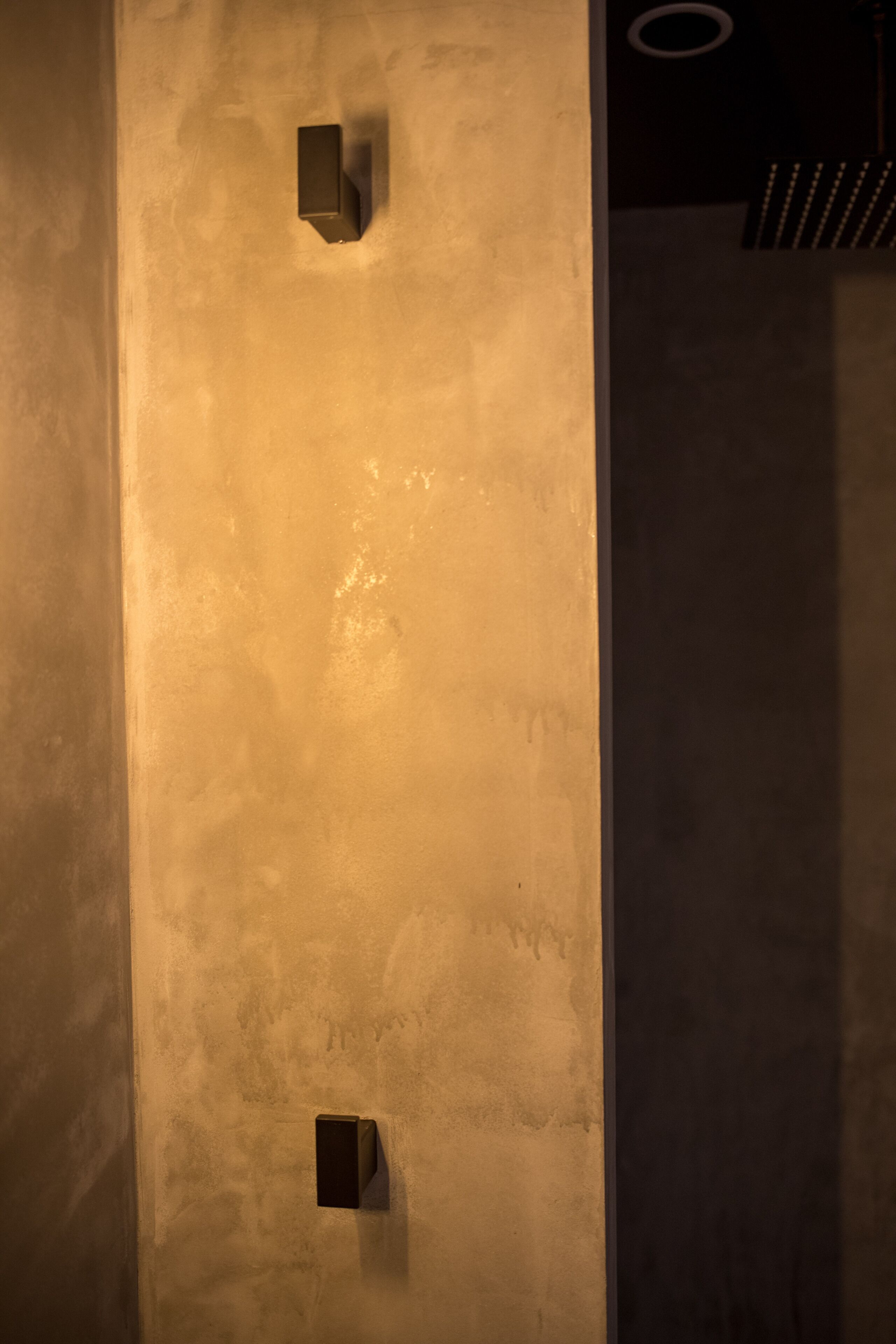 Un mur à texture avec deux luminaires encastrés.
