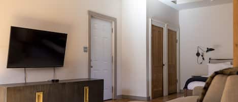 A modern living room with a flat-screen TV, a dark wooden cabinet, a beige sofa, and a patterned rug.