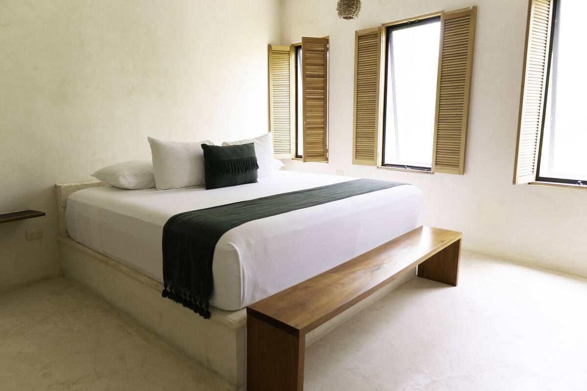 A bedroom with a large bed, wooden headboard, and a bench.