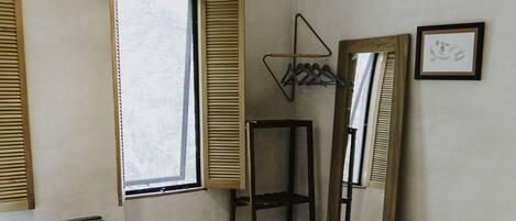 A room with two beds, a large window, a mirror, and a hanging light fixture.