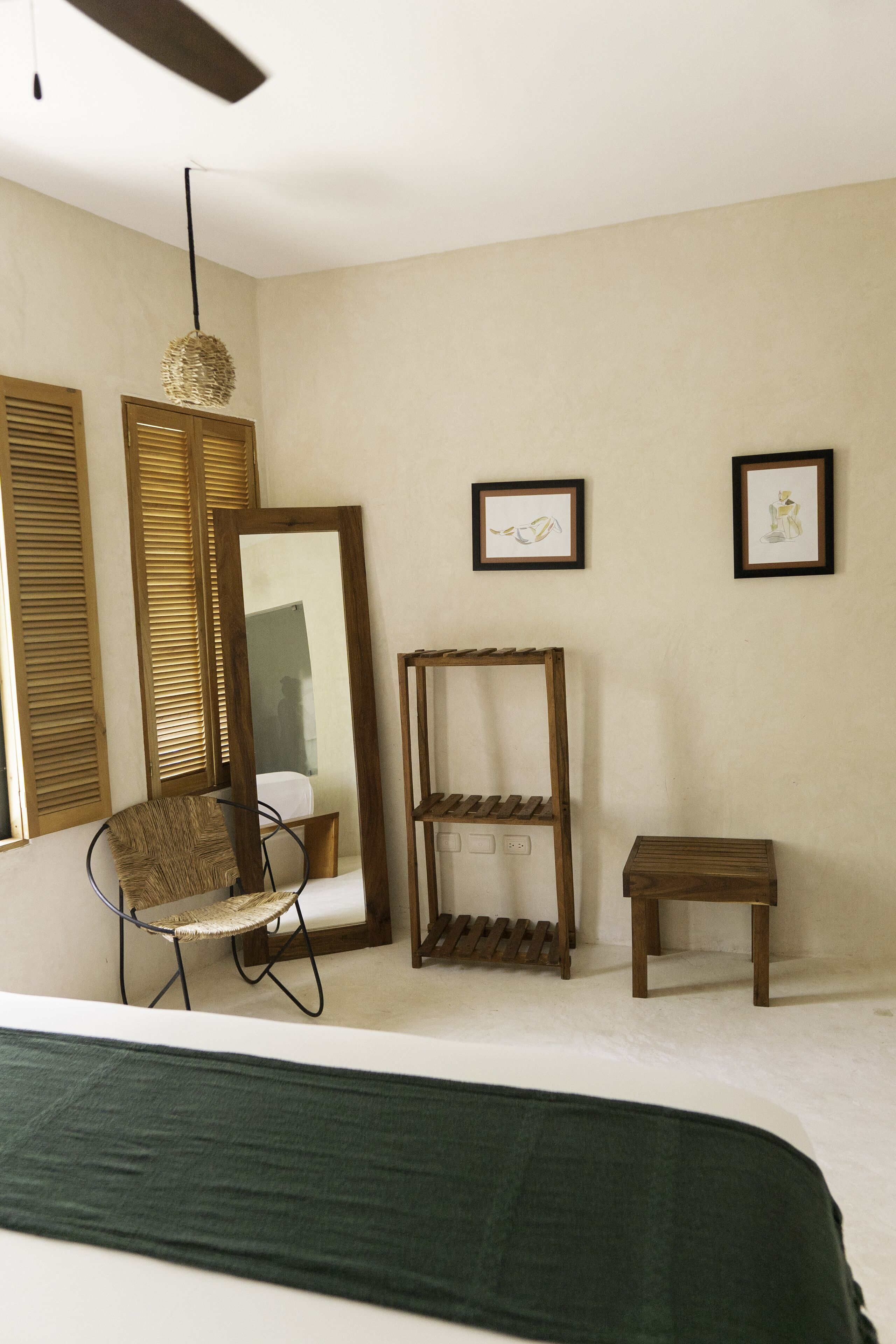 A bedroom with a bed, a chair, a mirror, and a shelf.