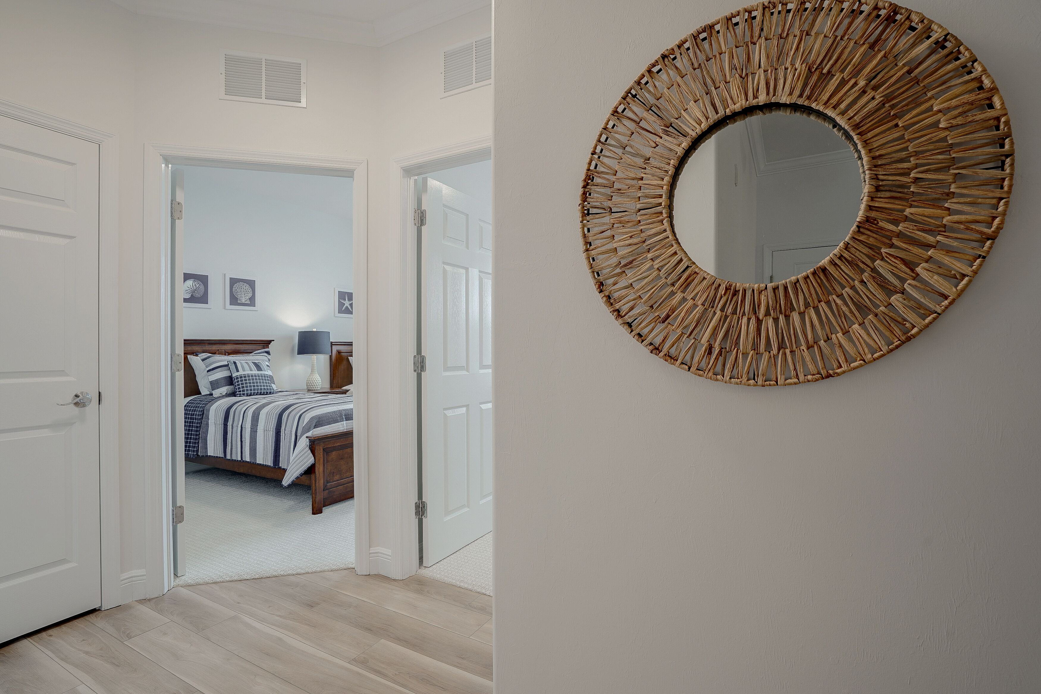 A bedroom with a bed, bedside table, and a wall-mounted mirror.