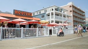 Eine Promenade mit Außenbereich beim Restaurant Hooters, ein weißer Zaun und ein mehrstöckiges Gebäude im Hintergrund.