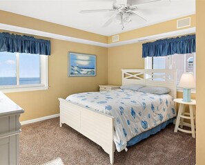 A bedroom with a bed, a nightstand, a lamp, a ceiling fan, and a window with a view. - The best of the best, 2BD direct Ocean Front with wide big ocean front  balcony . Relax and enjoy the ocean and the sun. (Ocean City)